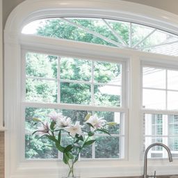 Timberwyck residence kitchen with white, granite countertops and arched window.